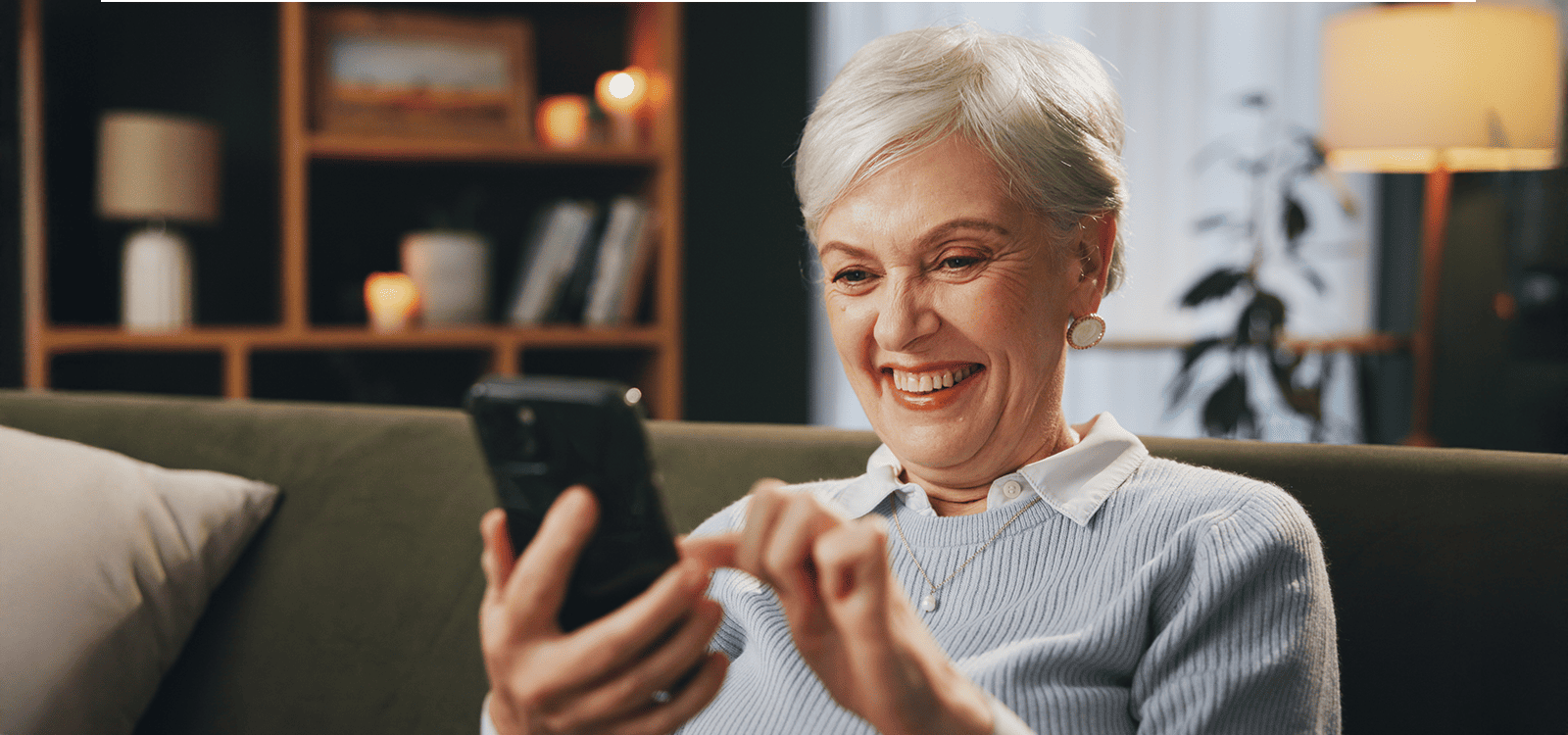 Aposentada sorrindo ao ver o crédito liberado no celular